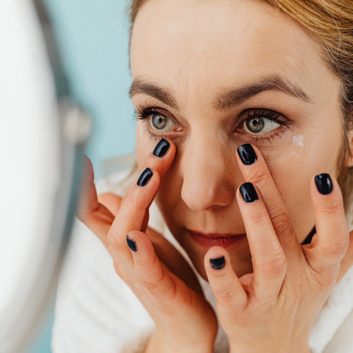 Woman applying a facial treatment in front of the mirror